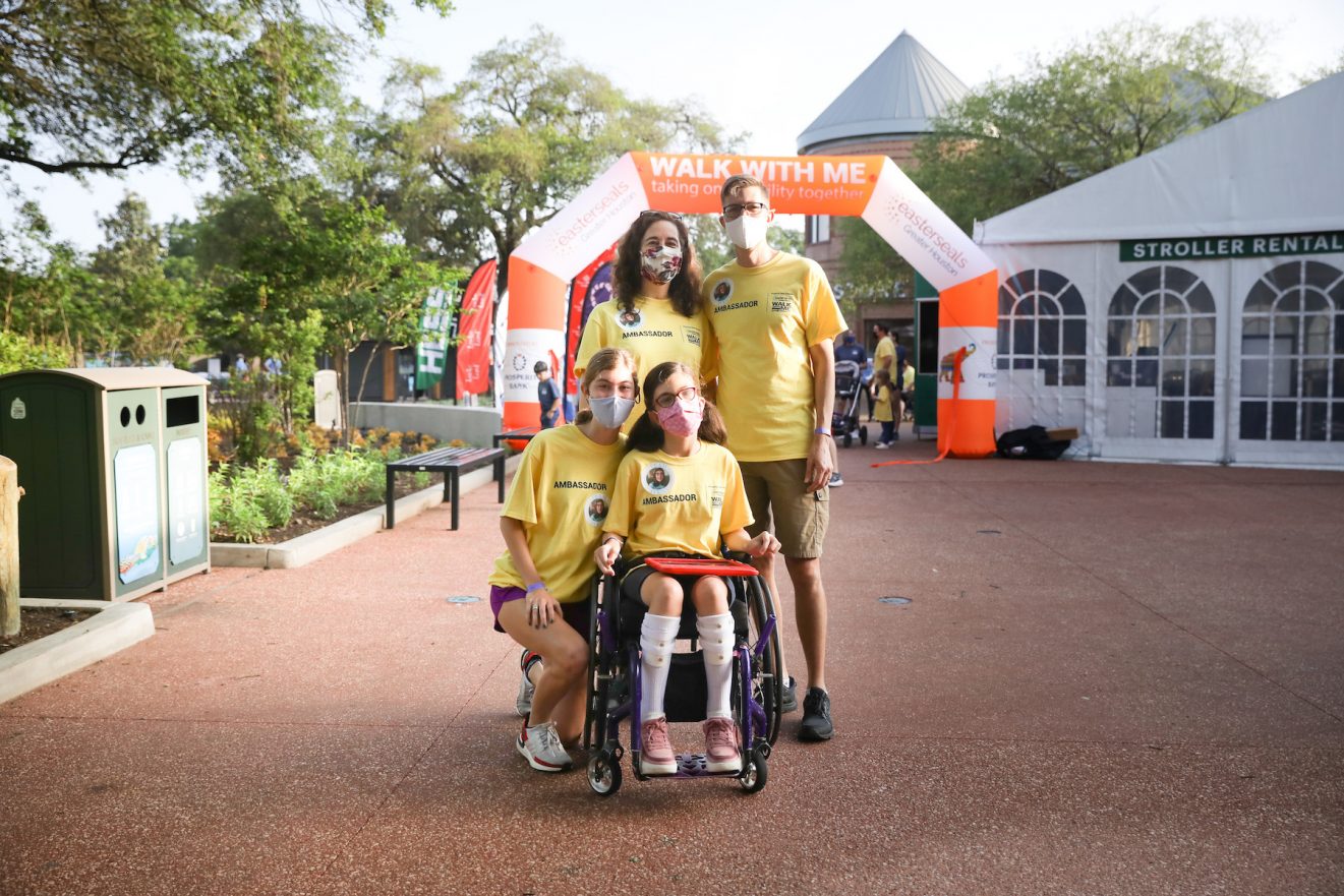 girl with in wheelchair holding ipad with family