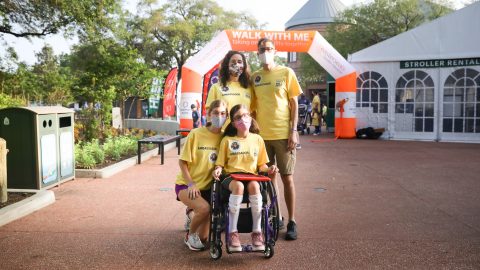 girl with in wheelchair holding ipad with family
