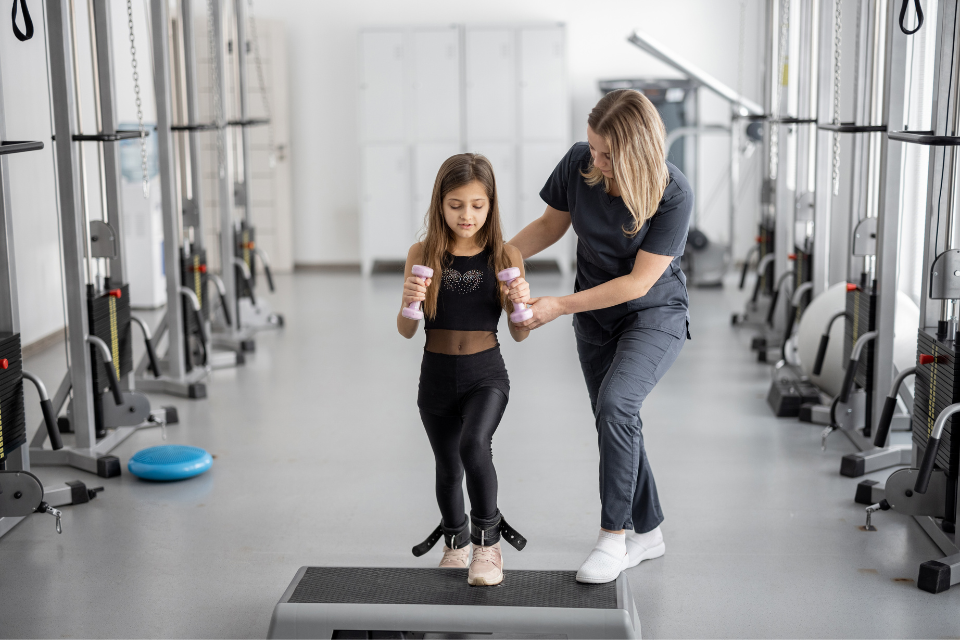 girl with small weights in gym with mom