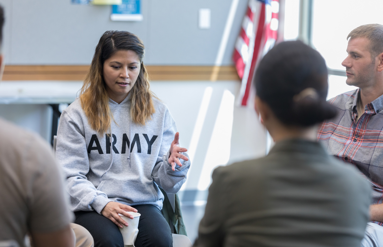 female with army sweatshirt talking with support group