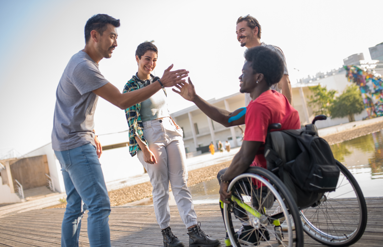 friends giving a high five to young adult male in wheelchair