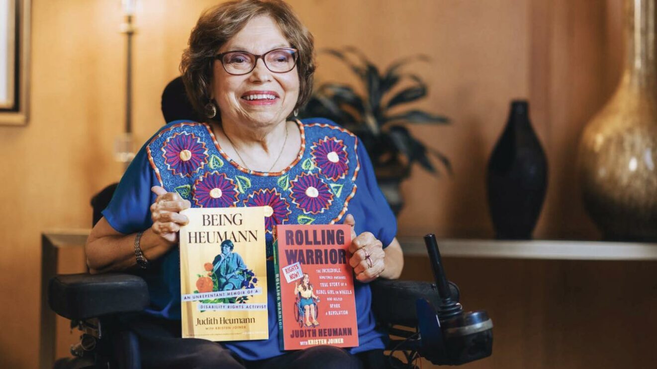 older woman in wheelchair holding books she wrote