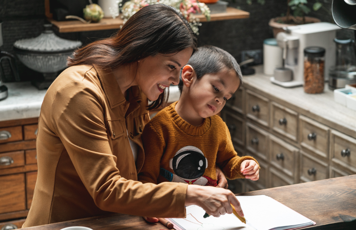 mom helping young son write in kitchen
