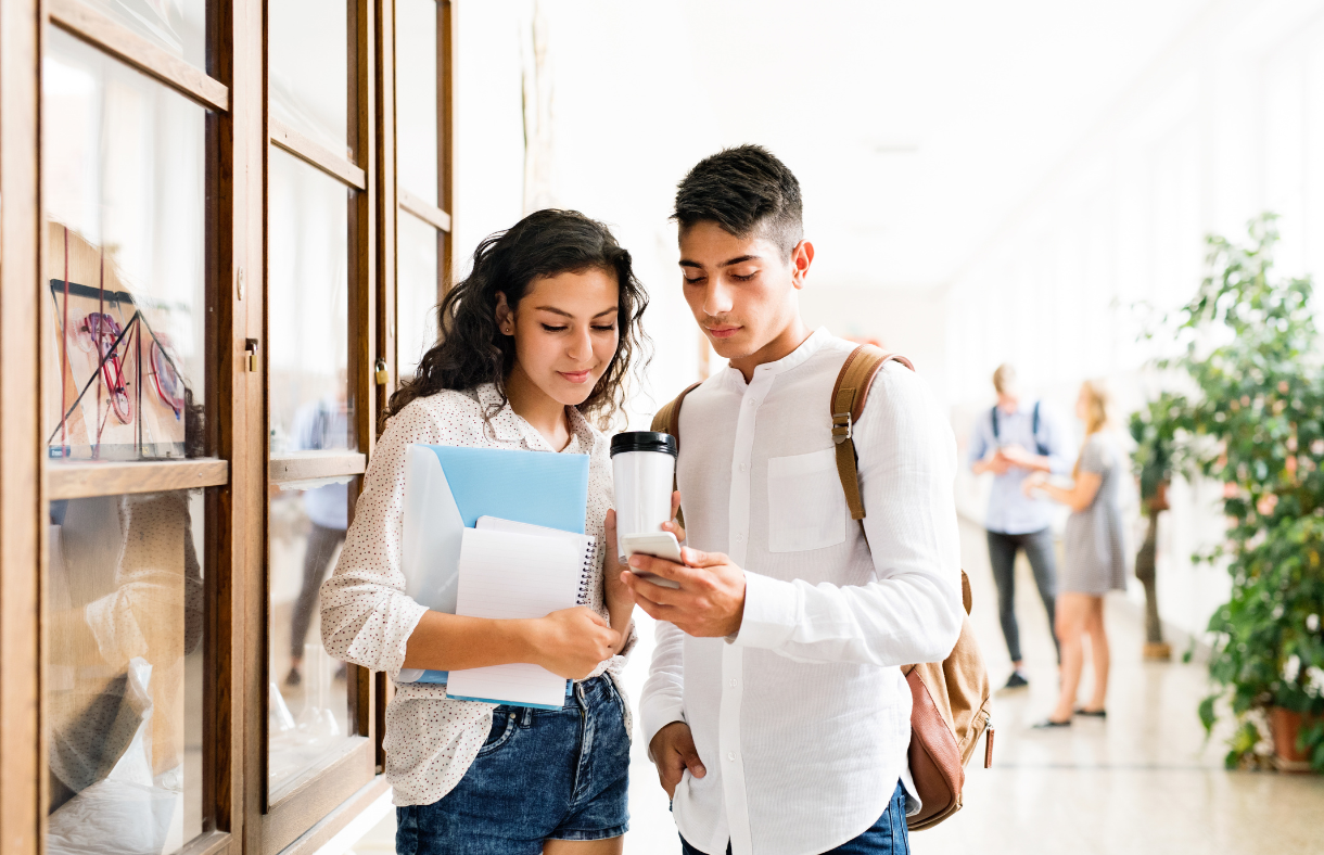 college girl and guy standing in hallway looking at phone