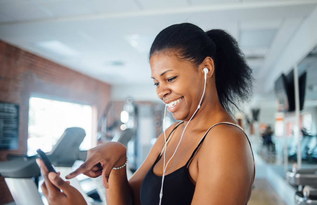 young adult female using phone in gym