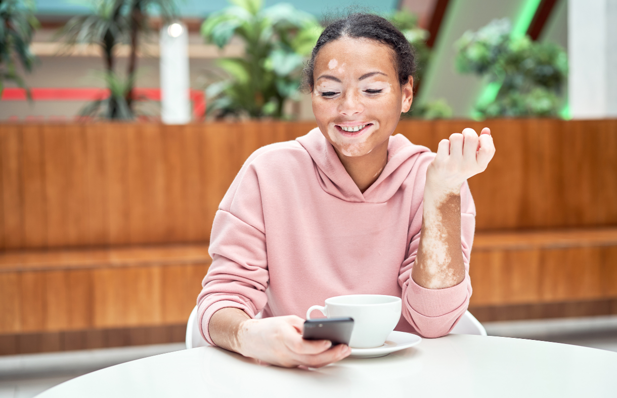 girl sitting at table with cup of coffee looking at phone