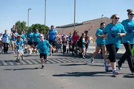 Outdoor run-a-thon with youngsters in teal-blue shirts front and center.