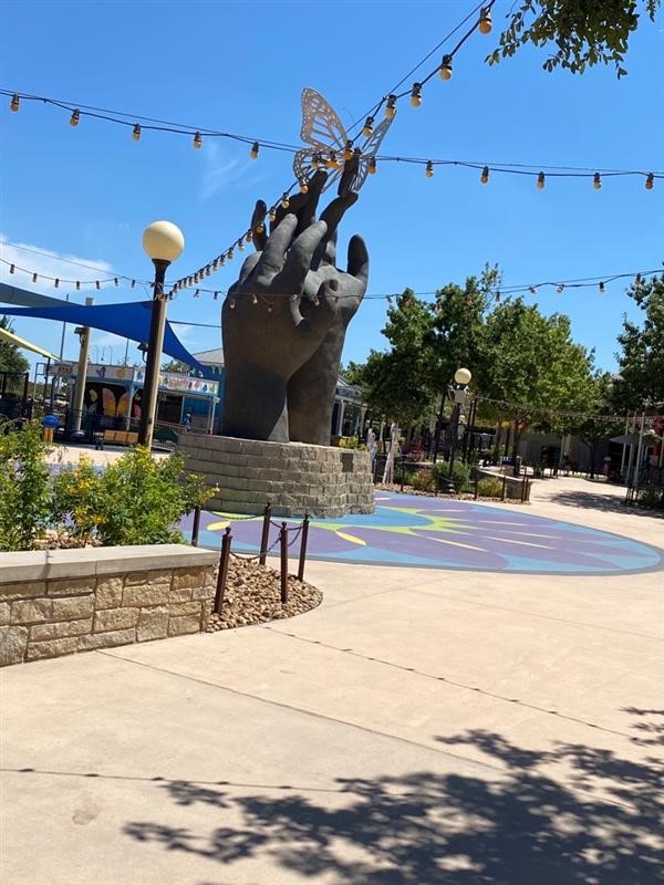 Entry plaza inside Morgan's Wonderland gates, featuring "Taking Flight," a pair of giant sculptured hands releasing a butterfly