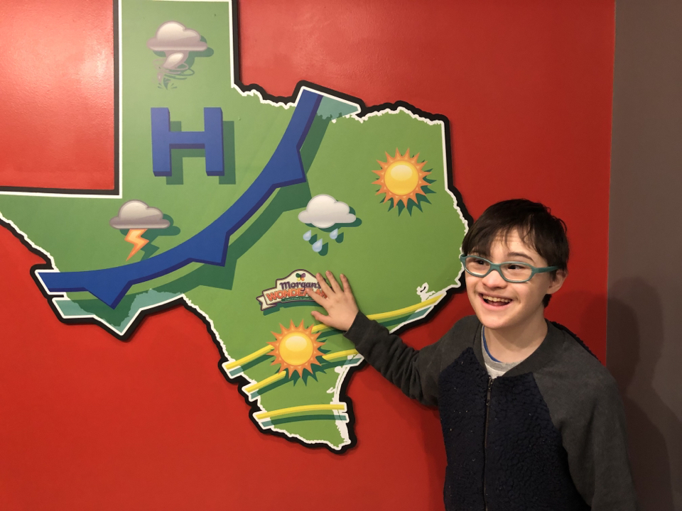 Vincent standing by wall painting that depicts the state of Texas and its typical weather patterns