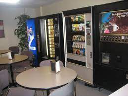 Office break room with tables and vending machines.