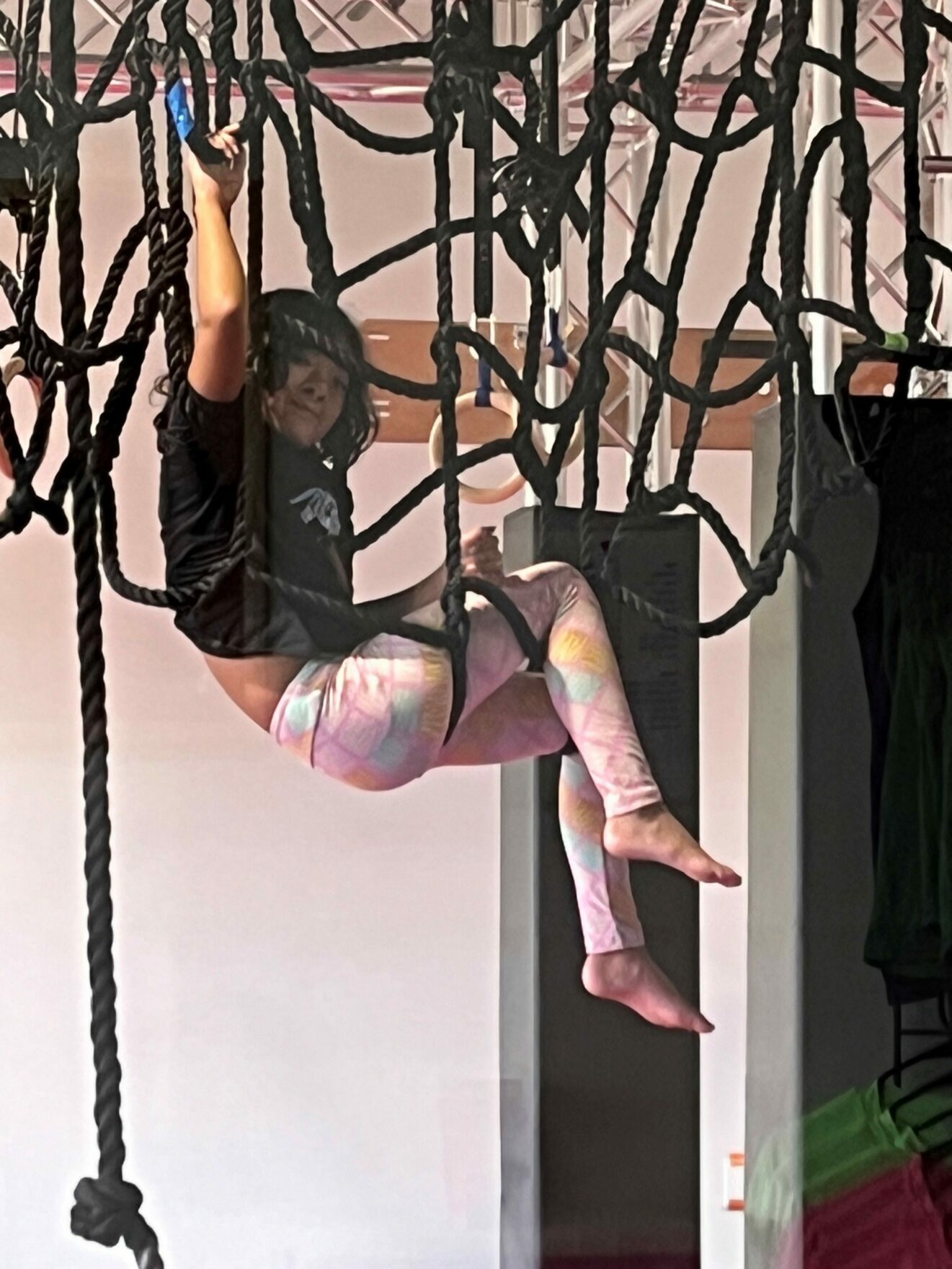 girl hanging from indoor netting