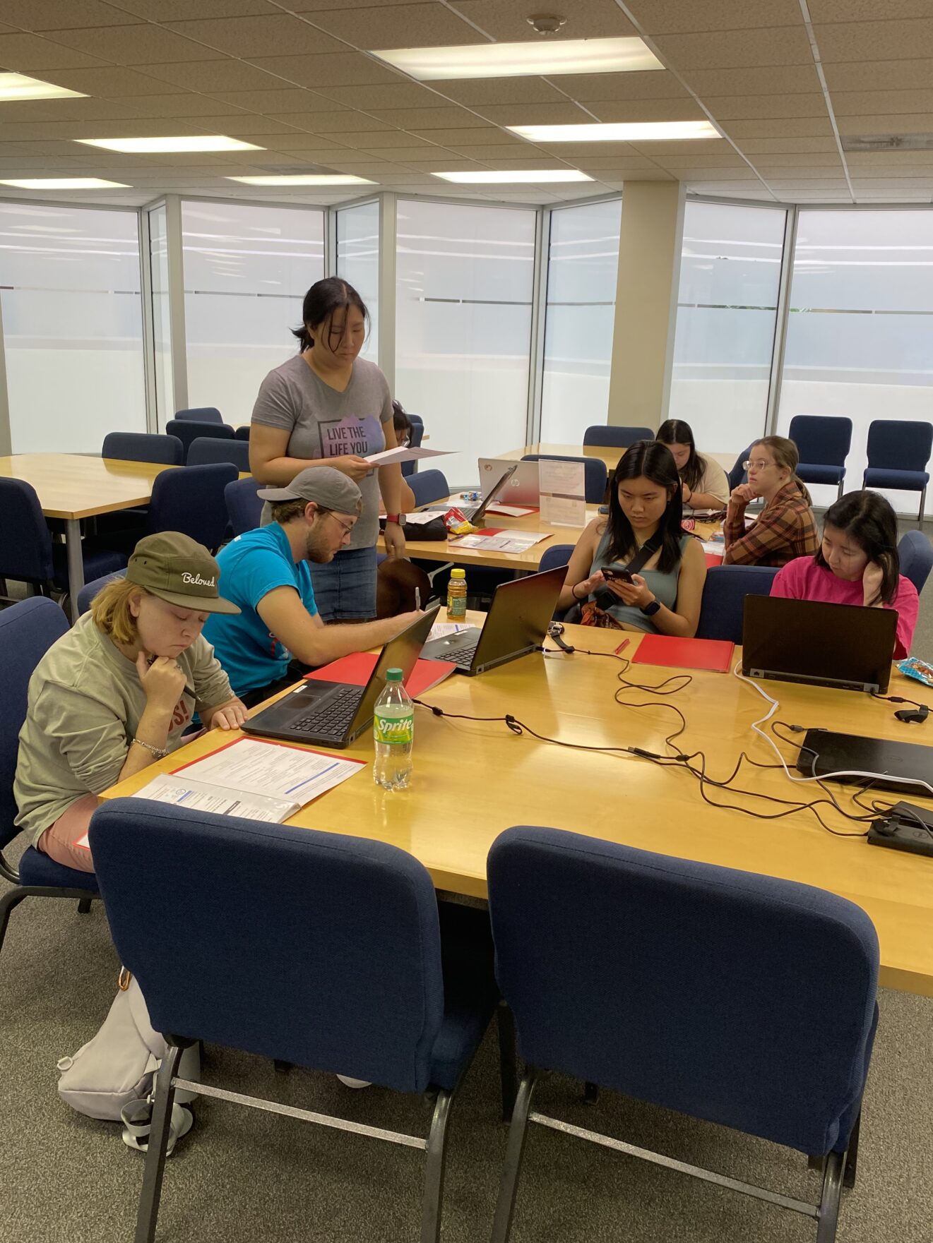 teen students sitting at table using digital technology