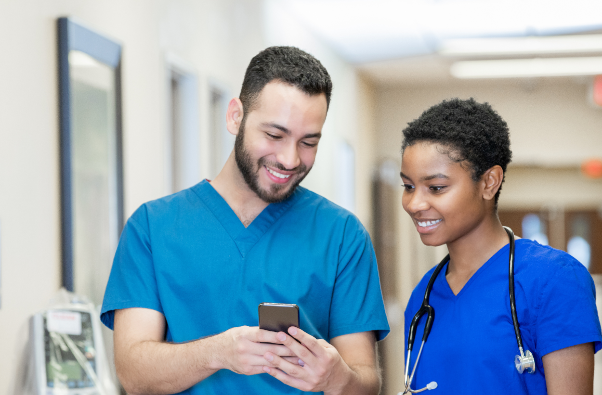 two nurses looking at phone together smiling