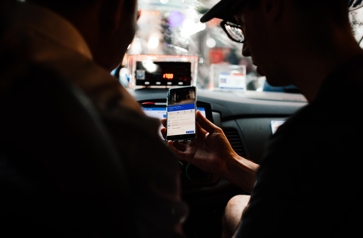 2 people looking at rideshare app inside vehicle