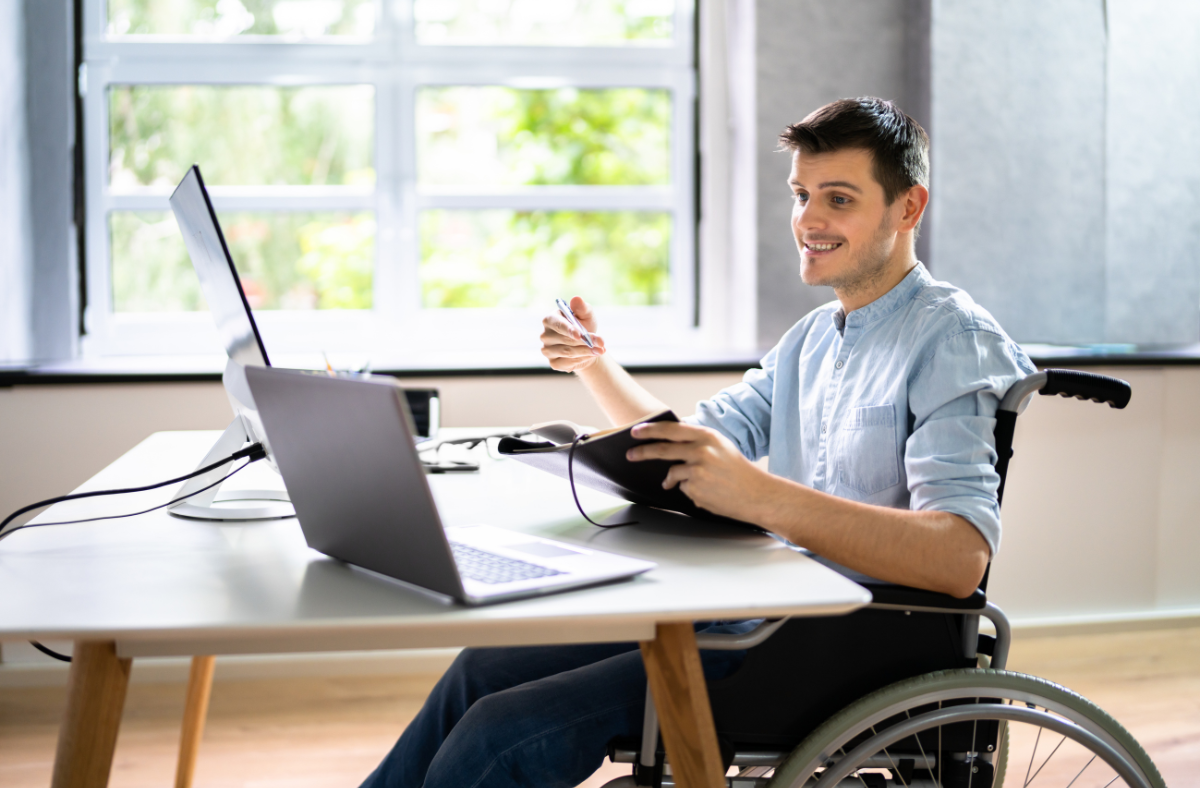 man sitting at desk looking at computer sitting in wheelchair