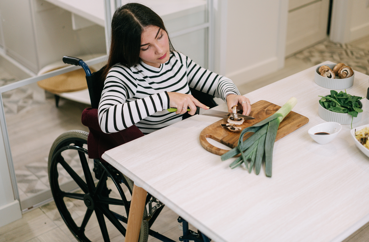 young lady in wheelchair cutting vegetables at a table