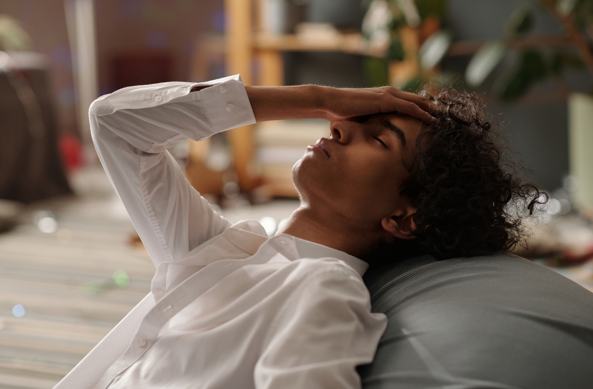 young man leaning back with hand on head appearing in distress