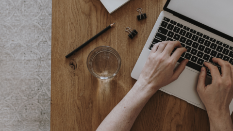 Older adult hands typing on laptop keyboard