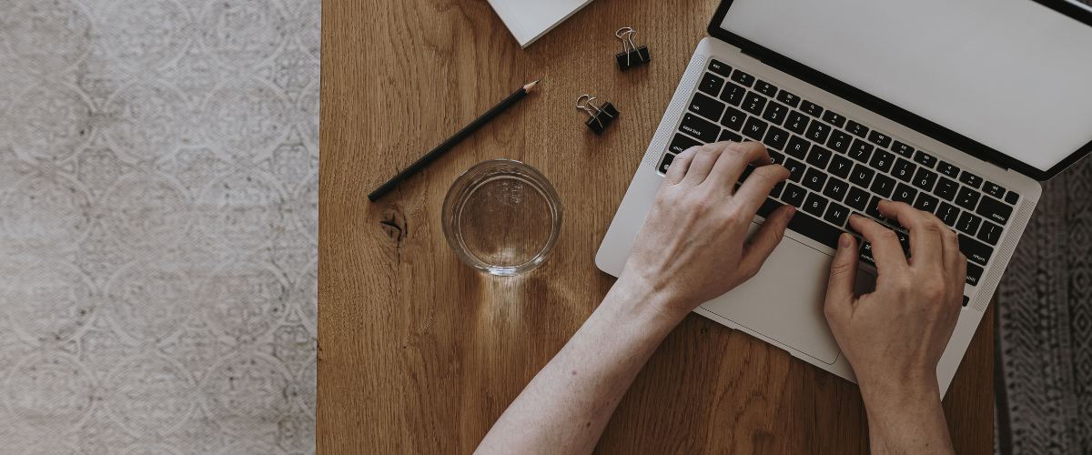 Older adult hands typing on laptop keyboard