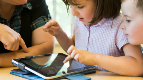 2 kids touching ipad for communication