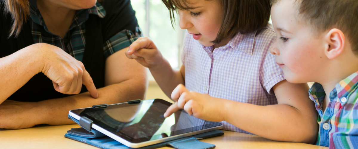 2 kids touching ipad for communication