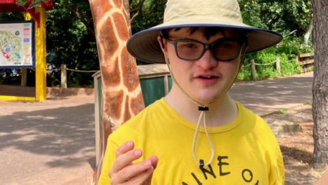 young man wearing hat and yellow shirt standing outside