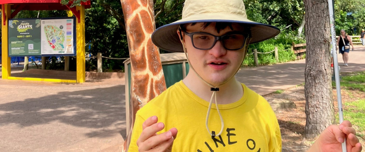young man wearing hat and yellow shirt standing outside