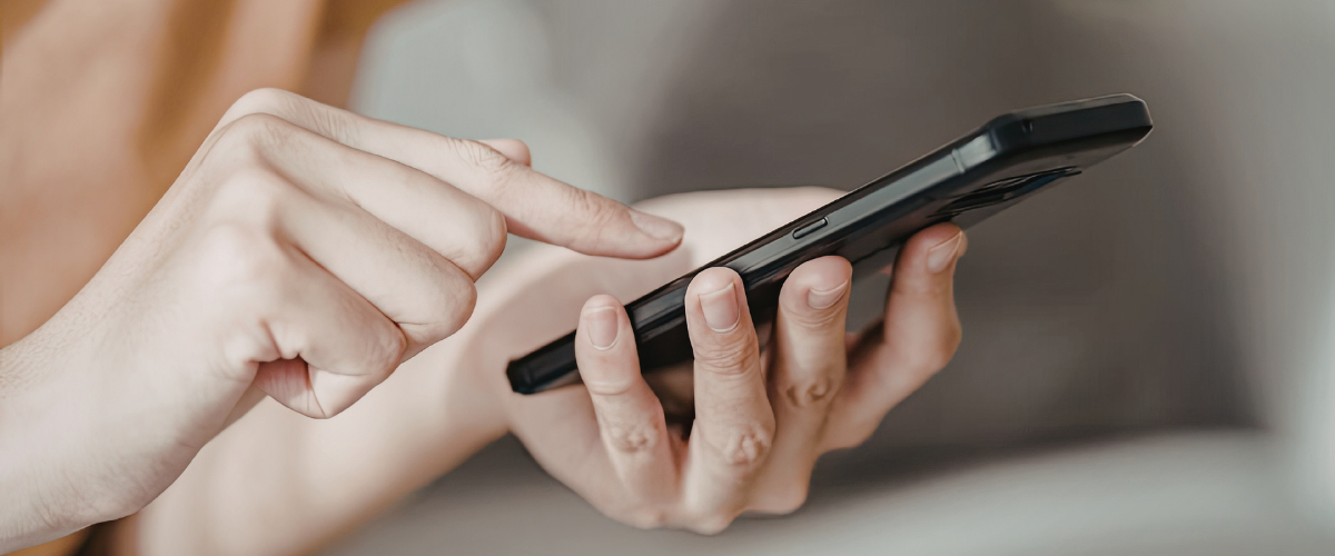 close up of one hand holding phone while other taps screen