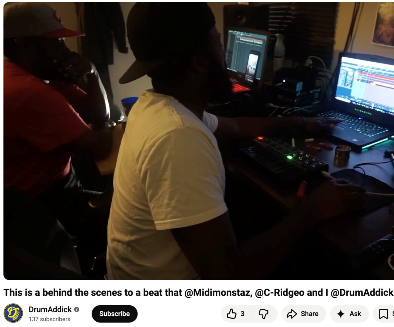 Two people sitting in a darkened recording studio; two lit monitor screens on their right