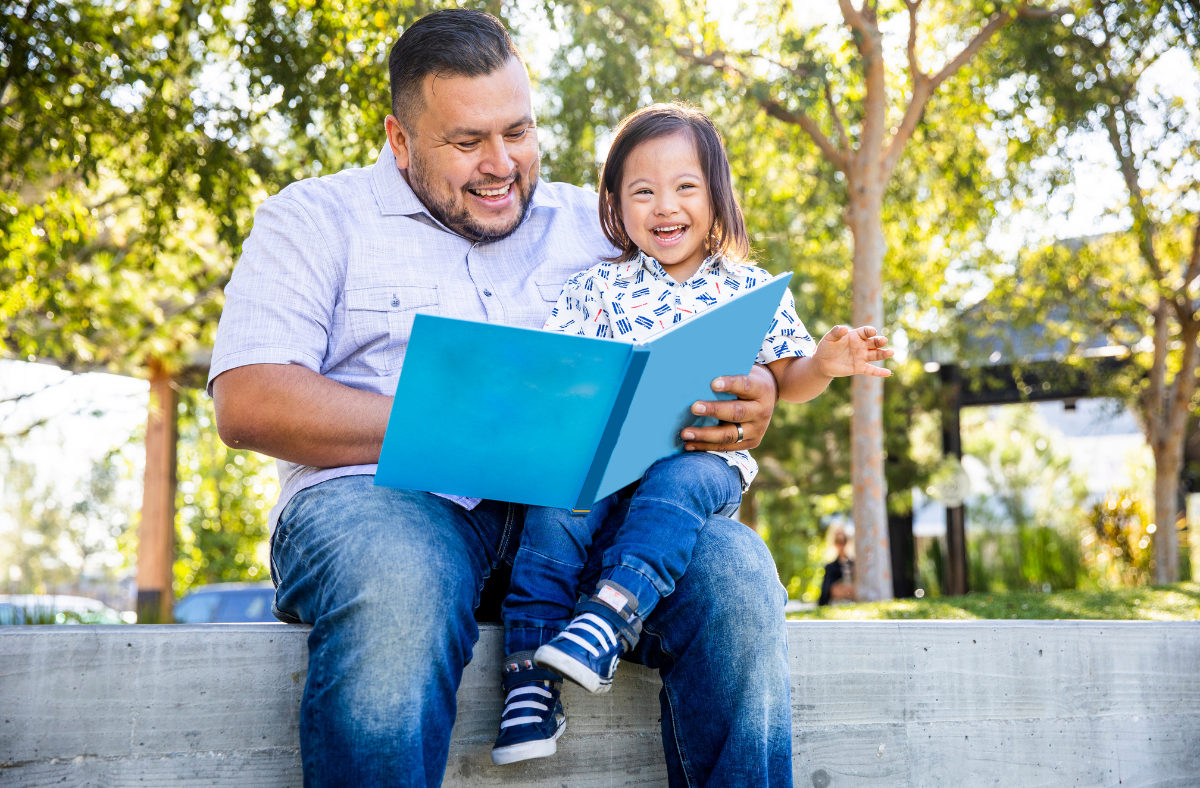 dad reading book to kid outside