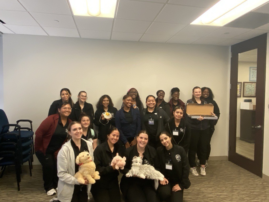 large group of students posing for camera front row holding Joy for All stuffed animals
