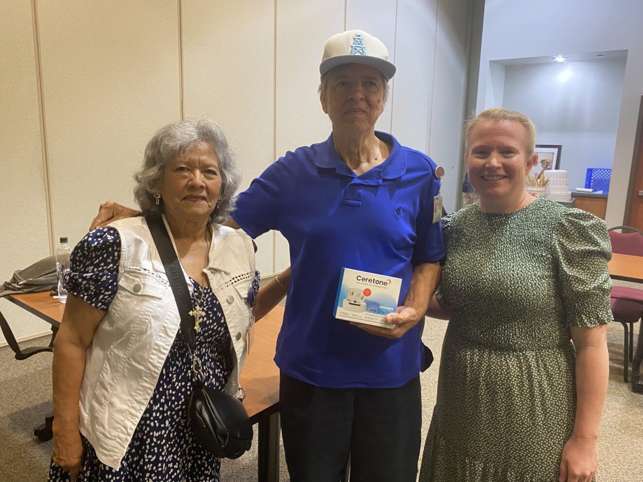 Three people standing facing the camera. Tall man in center is holding Ceretone box.