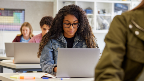 teens in classroom using laptops