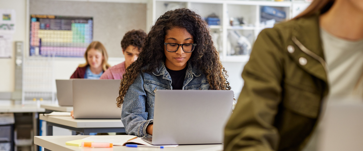 teens in classroom using laptops