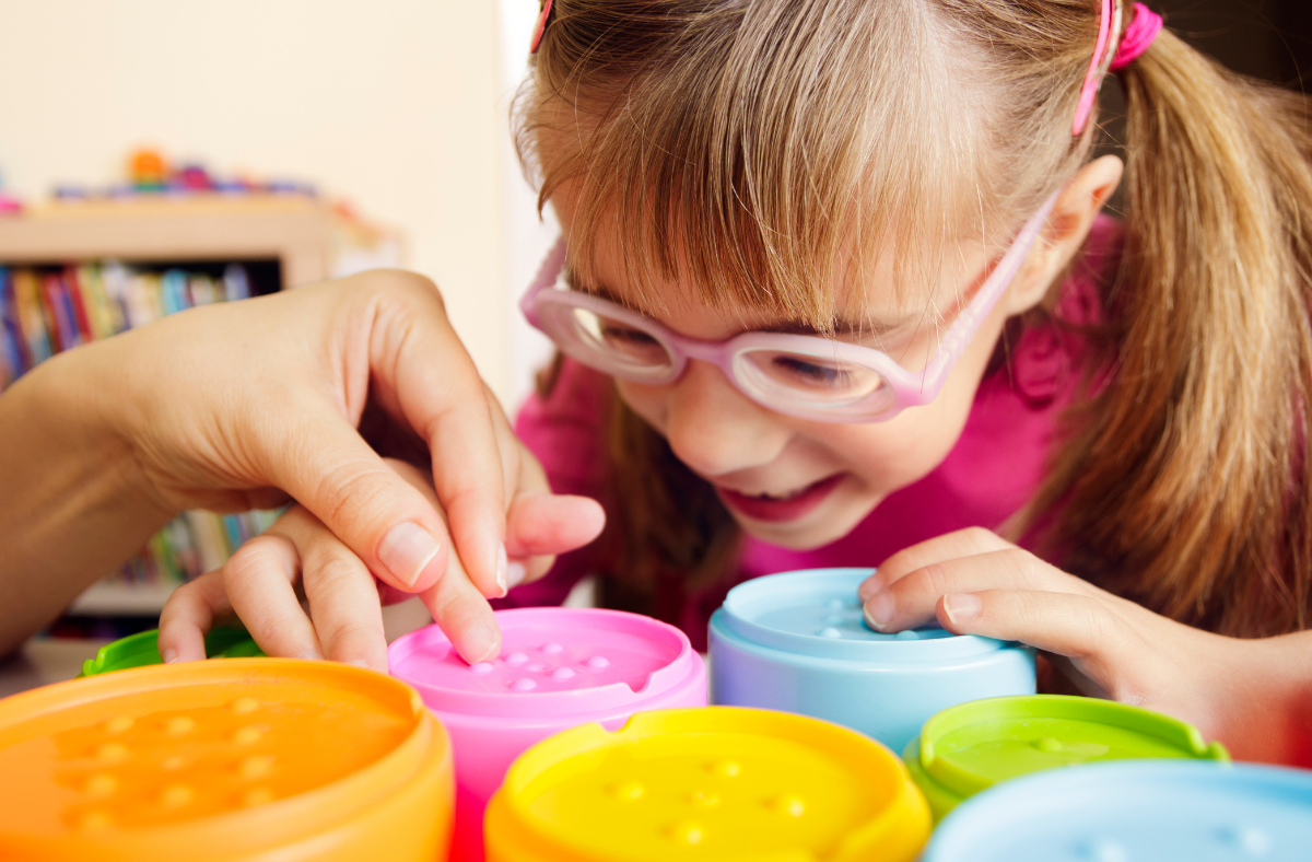 young girl wearing pink glasses in therapy touching cups