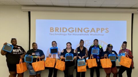 group of elqn participatnts standing in front of classrooms holding orange bags