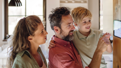 family looking at smart home device on wall